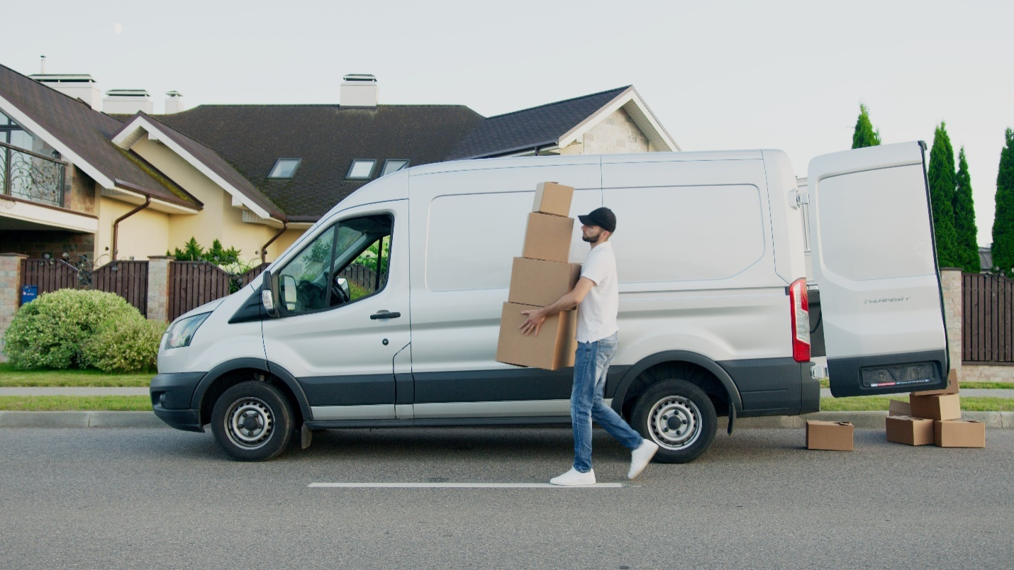 A person wearing a white t-shirt carrying boxes